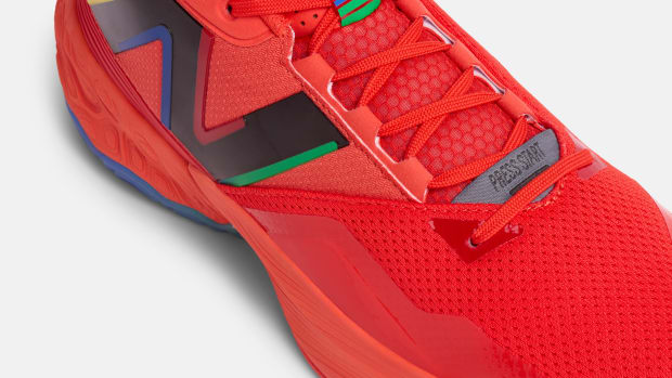 Side view of a red and black New Balance basketball shoe.